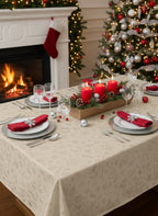 Tovaglia natalizia Ramis avorio con stelle dorate su tavola imbandita con camino e decorazioni natalizie